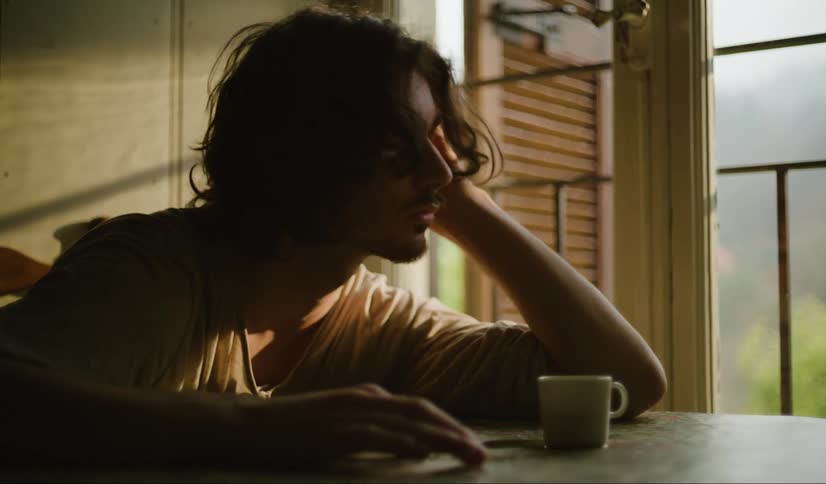 Bored man with a beard and a white shirt sits at table