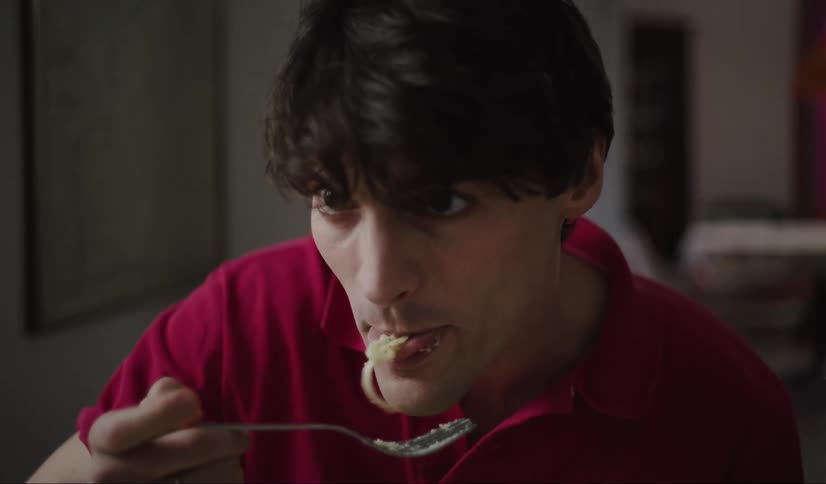 A man wearing a red polo tshirt casually enjoying spaghetti