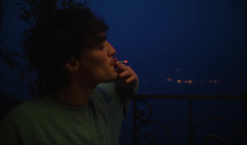 A man smoking on the balcony at night