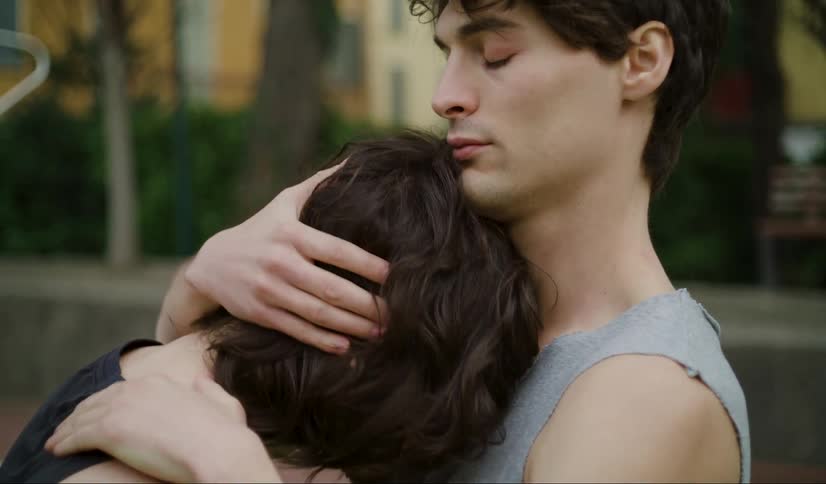 A man and woman are hugging outside