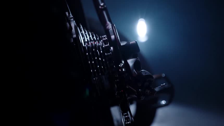 A single light illuminates the gear and chain on a bicycle