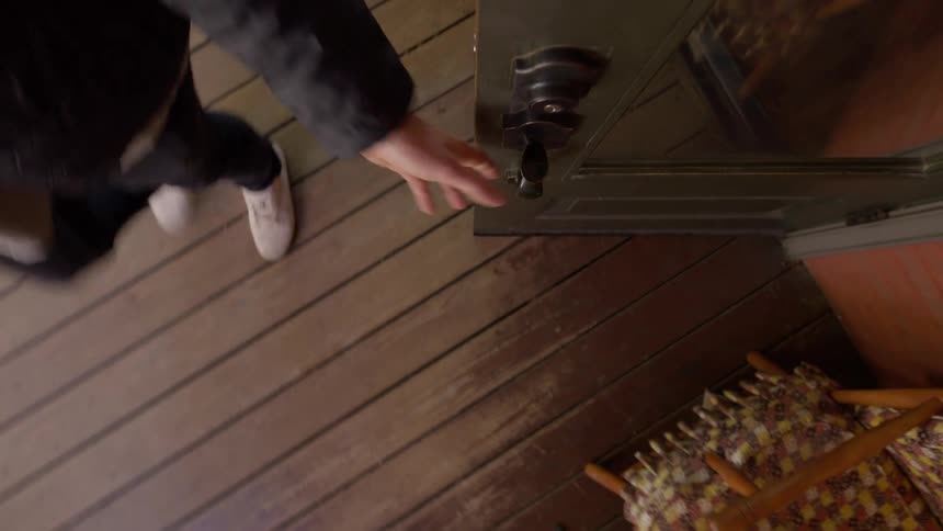 Man exits building door onto wooden porch