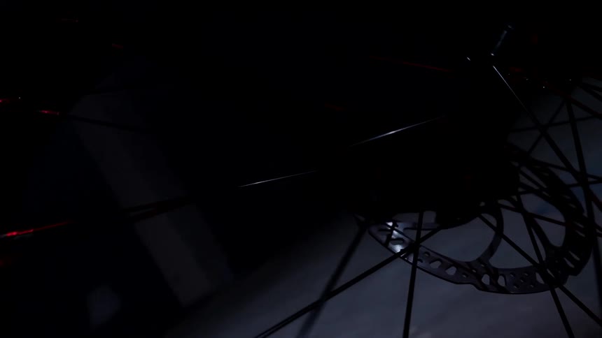 In a darkened space the spokes on a bicycle wheel gleam