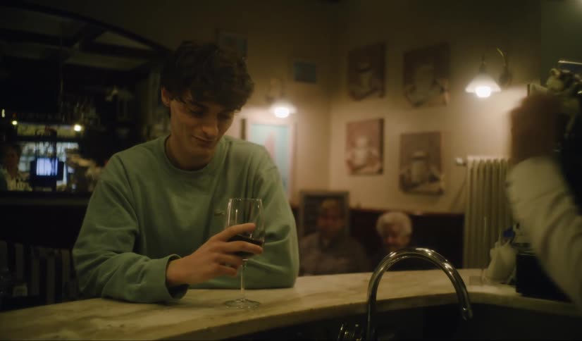 Man sitting at a bar counter being served with a wine glass