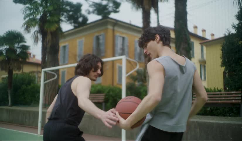 Two men are playing basketball outside