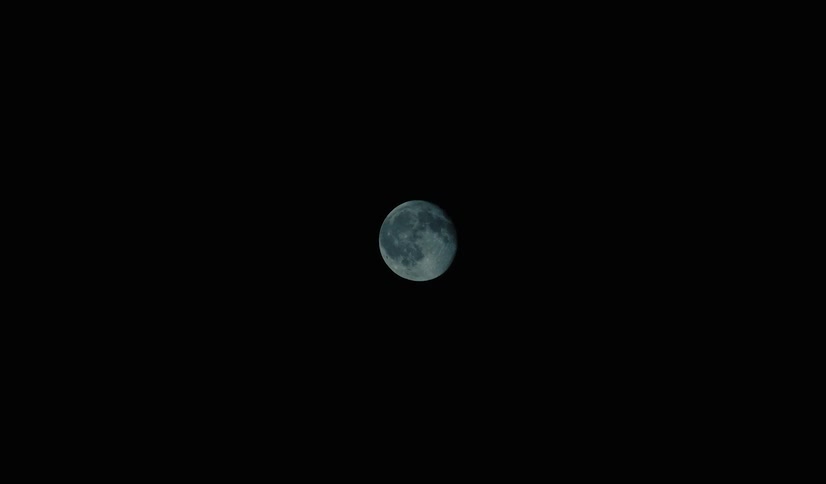 The moon glows in the darkness of space