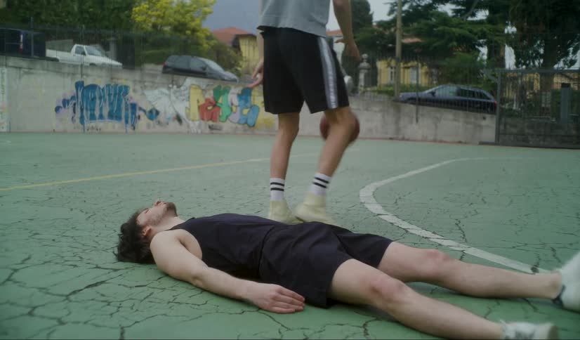 Young man laying on the floor of a basketball court