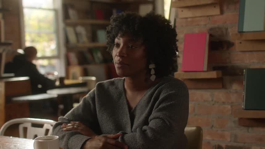 A woman is talking to someone with a cup of coffee in front of her