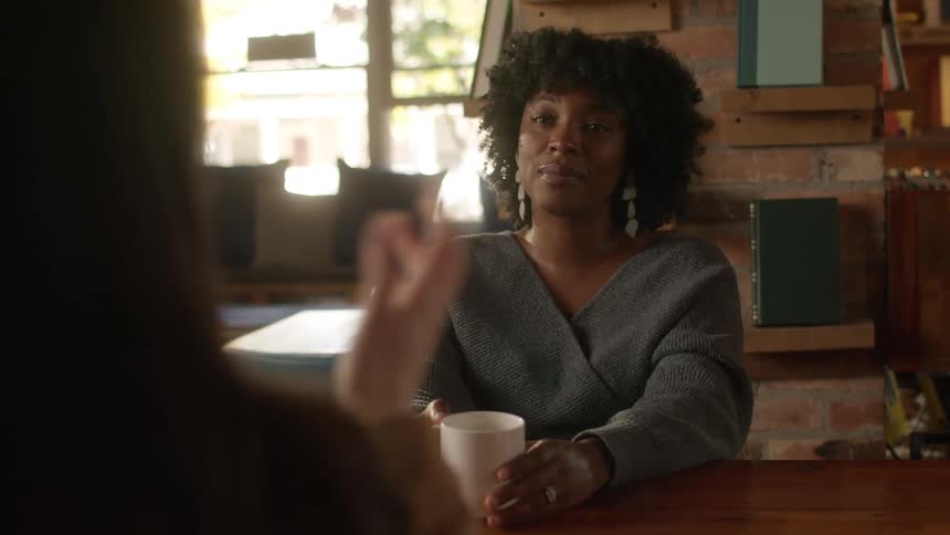 Seated at a table in the cafe women smile and engage in friendly conversation with each other
