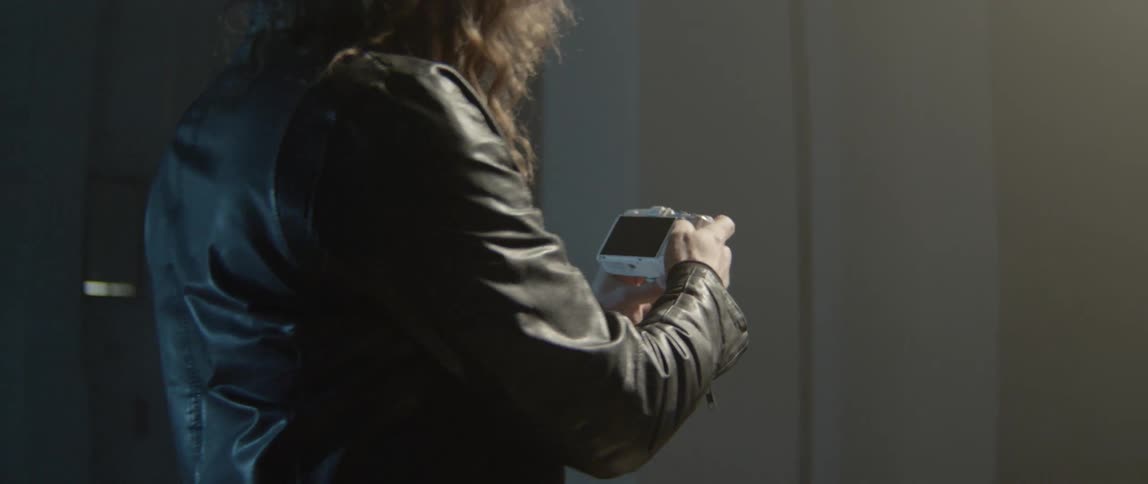 a photographer in leather using a modern digital mirrorless camera.