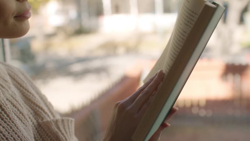 Woman wearing a white sweater reads a book