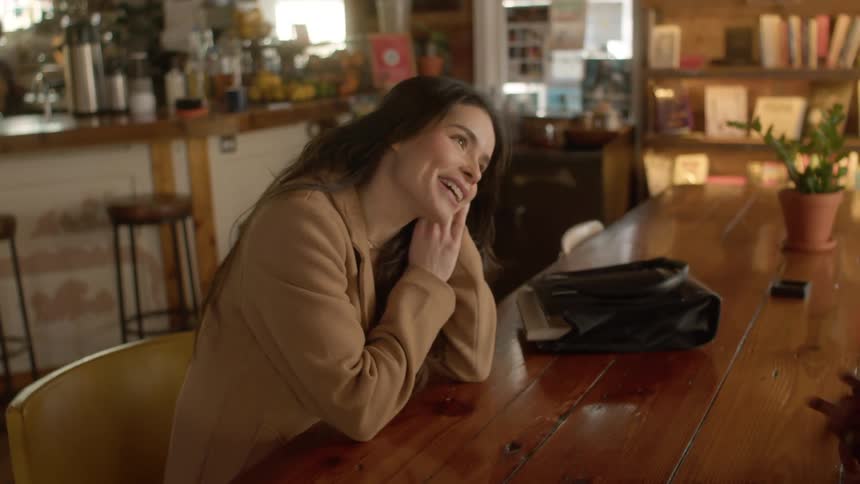 Two women are sitting and talking at a table in their warehouse