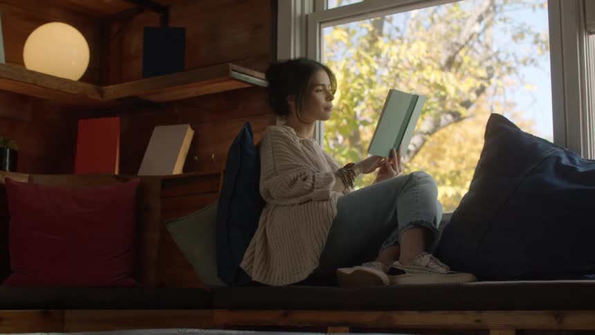 Woman sitting and reading a book next to the window