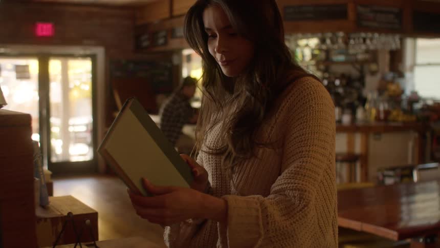 A woman picks up a book in the pub