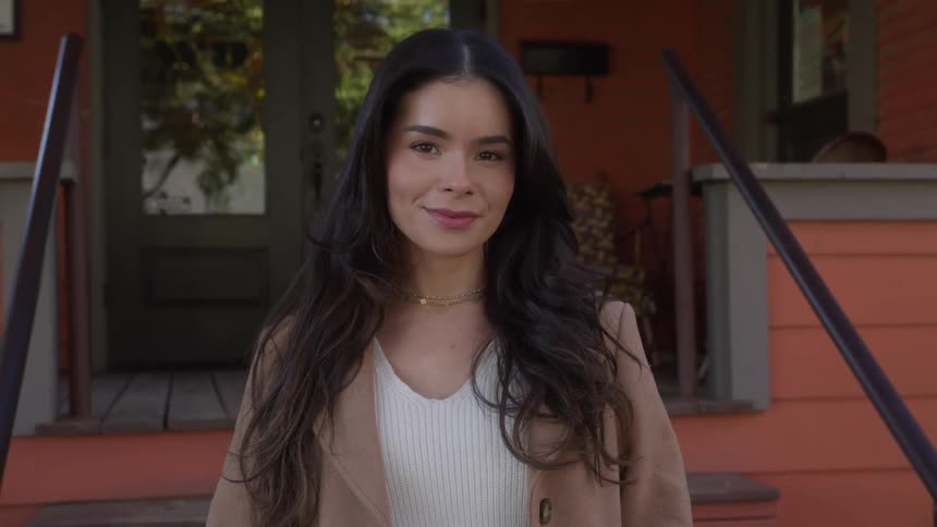 Woman standing outside a small store looks at the camera