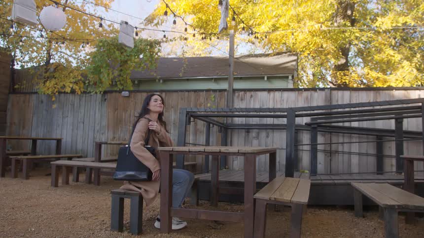 Woman sits on the outdoors table of a coffee shop