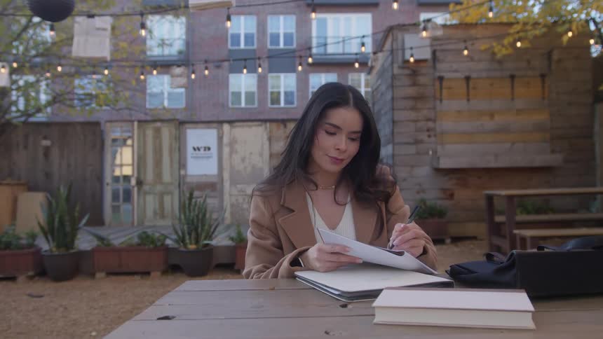 Server brings coffee to a woman sitting outside the coffee shop