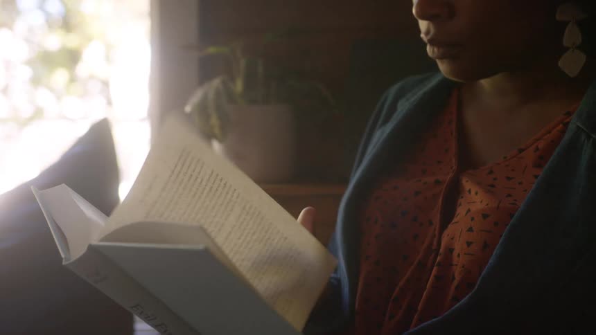Woman with curly hair and a blue jacket reads a book