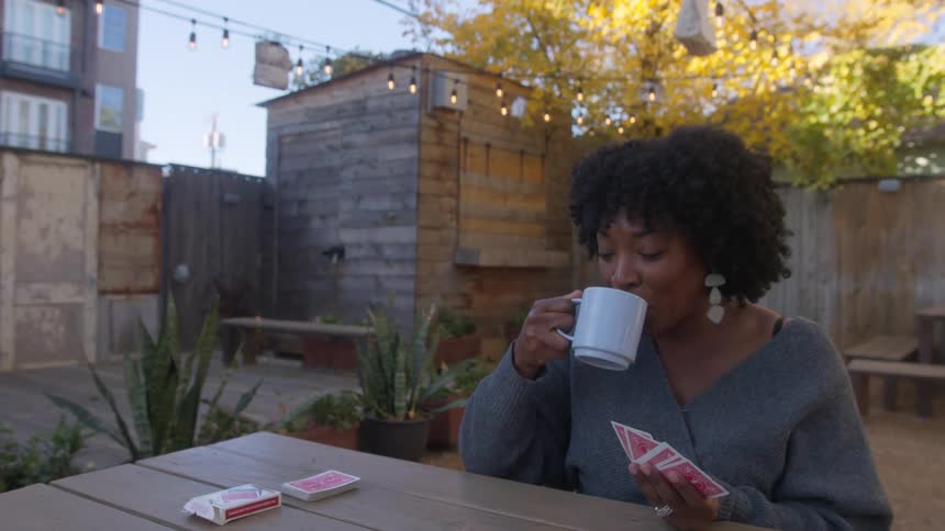 Seated at a table in the cafe yard women share smiles engage in conversation and enjoy a card game together