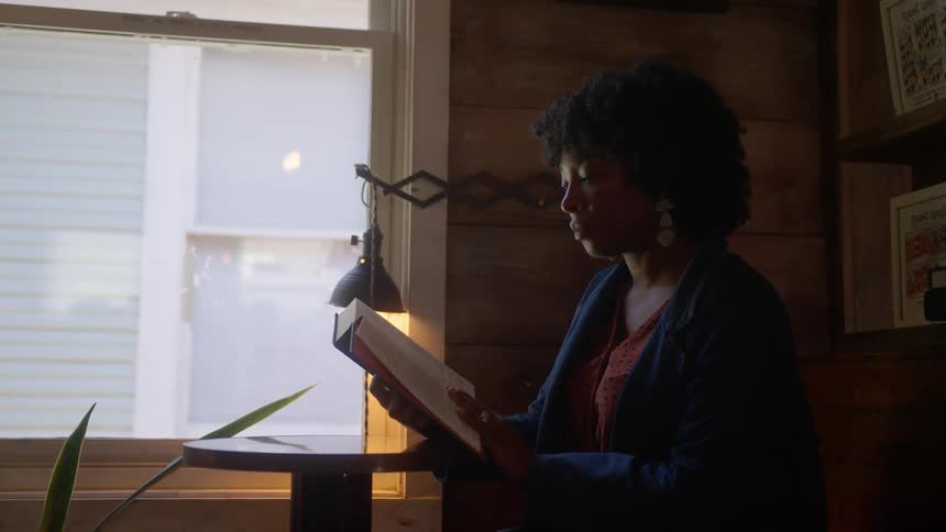 A woman is sitting and reading a book attentively