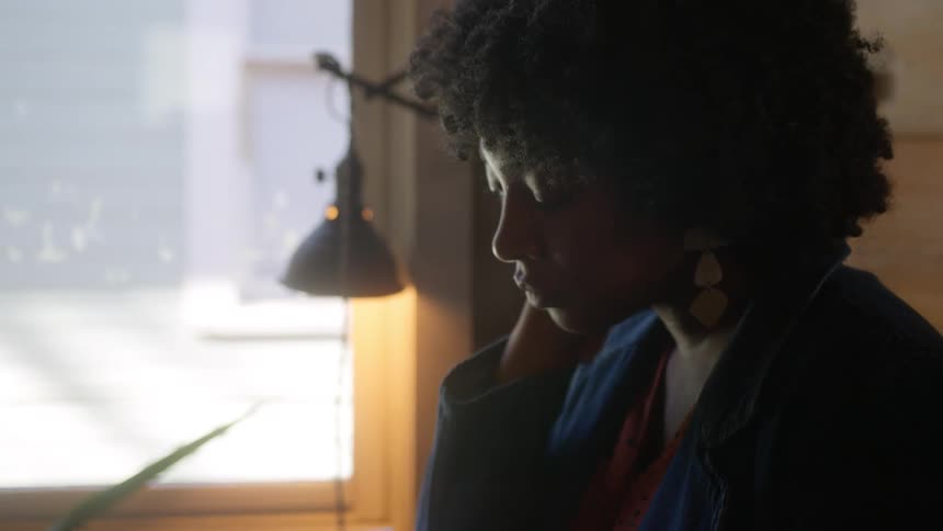 Close up of woman with curly hair and earrings reads a book
