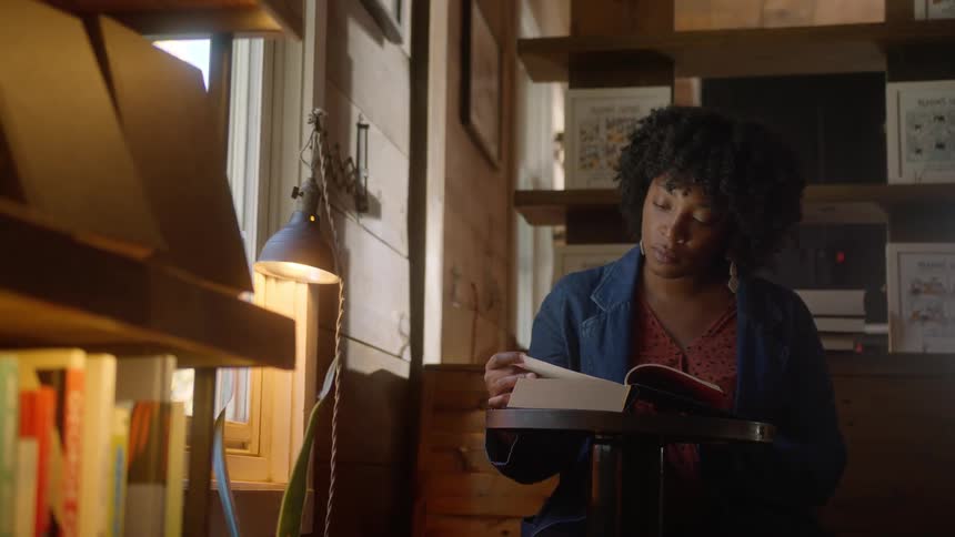 A woman is reading a book by the window