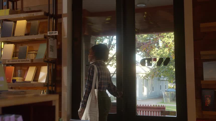 A woman enters an establishment opening a glass door