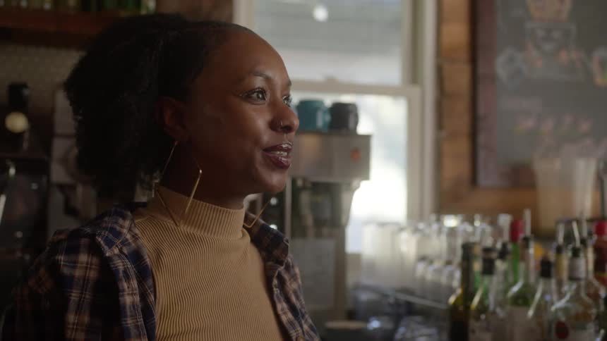 A woman is talking behind the bar