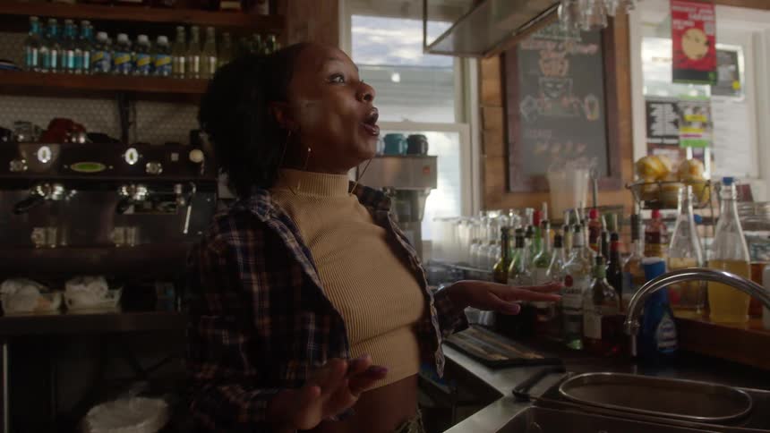 Woman stands up after looking under the sink and smiles as she speaks