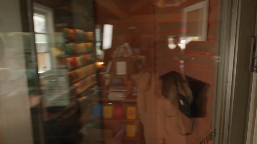 Woman enters bookstore through door with reflective glass