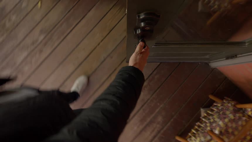 Top view of a wood deck and door being opened from the outside by man entering the building on a fall day
