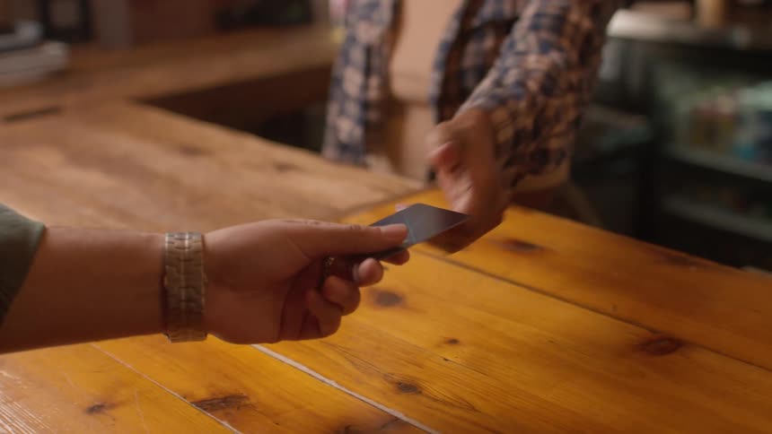A customer hands their credit card to a woman behind the counter