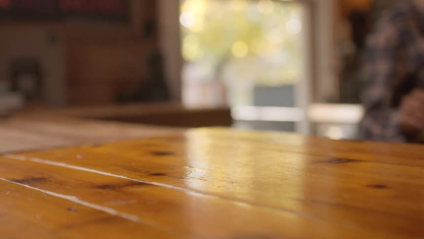 A female bartender picks up a glass of beer from the bar and puts it somewhere else