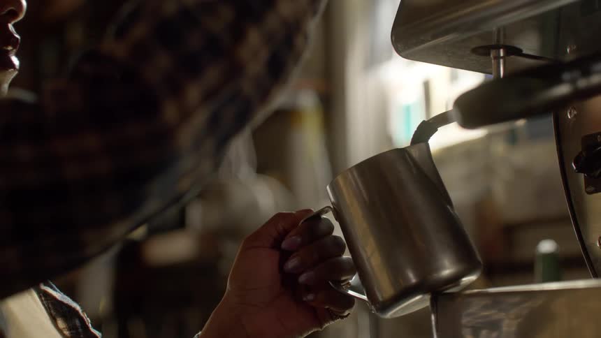 Woman makes wipes machine after frothing coffee in metal pitcher