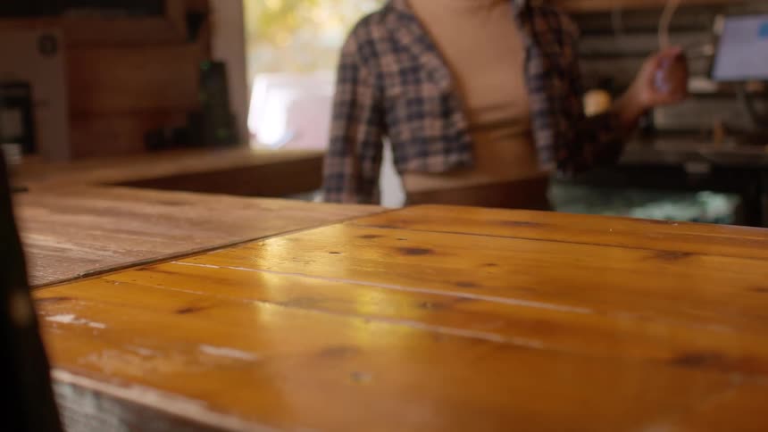A female bartender takes a credit card from a male patron over the bar