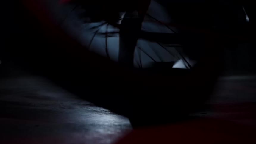 Silhouette of a person spinning on a motorcycle indoors