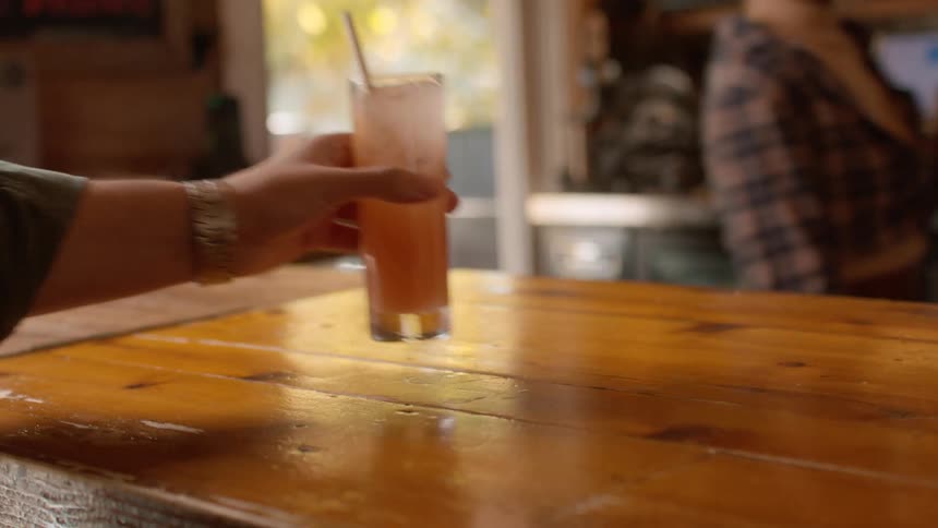 Black woman passes drink across counter to person