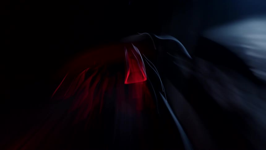 Motor bike sits parked in dark area lit by a blue light and a red light