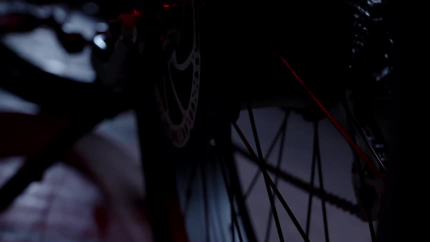 Red light runs on the spokes of a bicycle on a gray floor