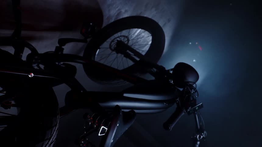Motorcycle sits parked in foggy darkness lit by light