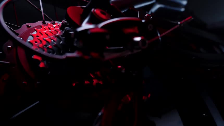 Close up of the gears of a bicycle under red lights