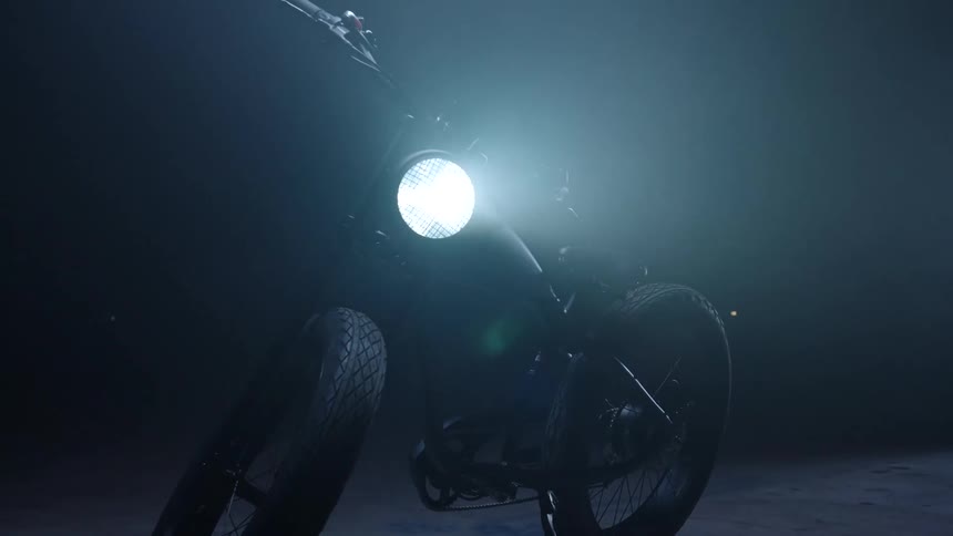 Bicycle with headlight on parked in a dimly lit room