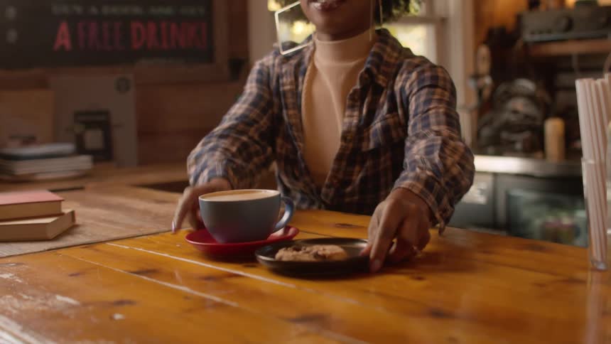 Employee serves coffee and a cookie to a customer