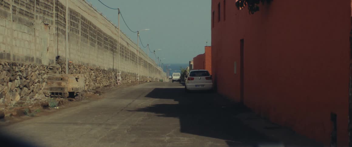 Cars on a narrow street under a blue sky