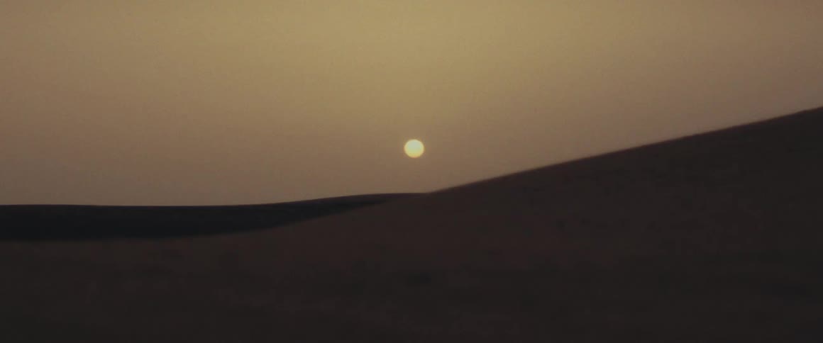 The sun sets over sand dunes in the desert