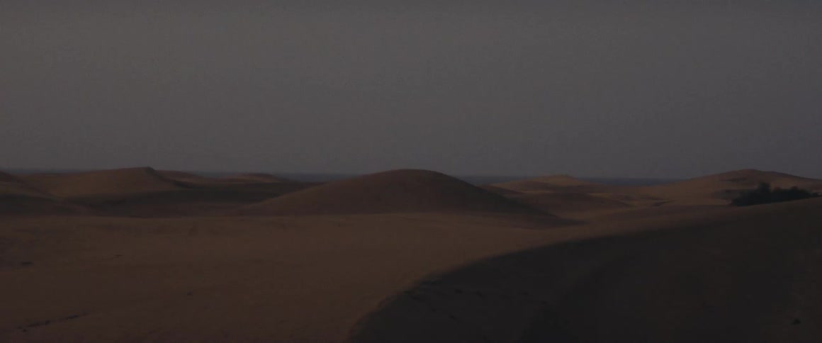Desert landscape with sand dunes and hazy sky after sundown with very little light