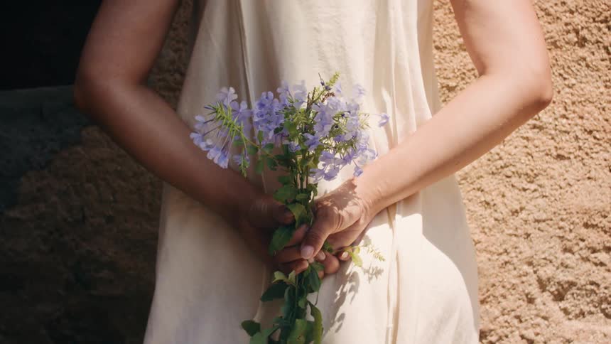 A white woman holds a bouquet of flowers