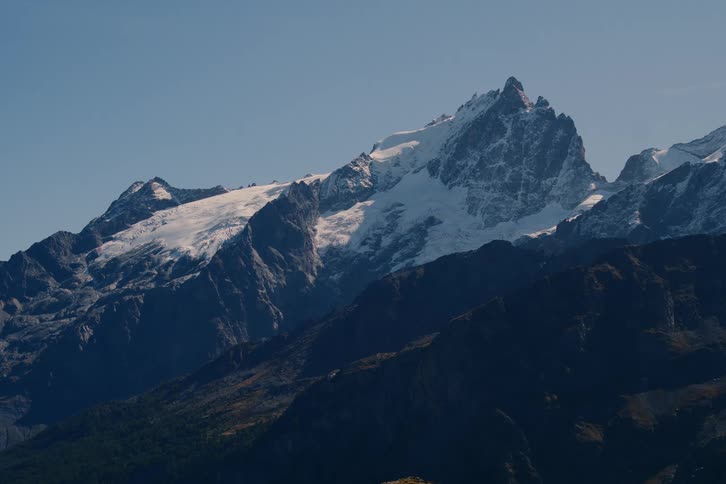 A rocky and jagged mountain peak is covered in a layer of snow