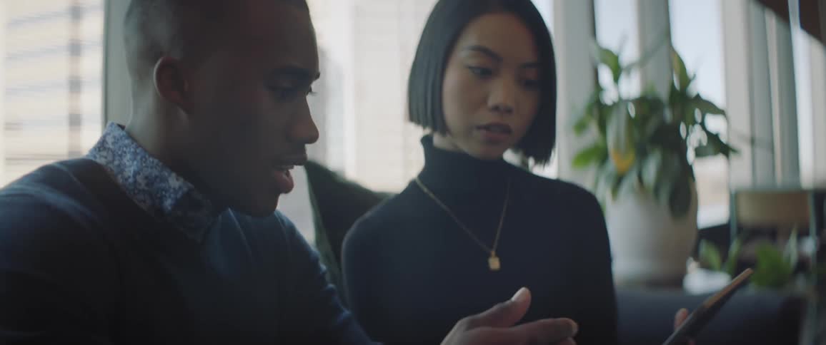A man analyzing a project on a tablet with a woman in the office