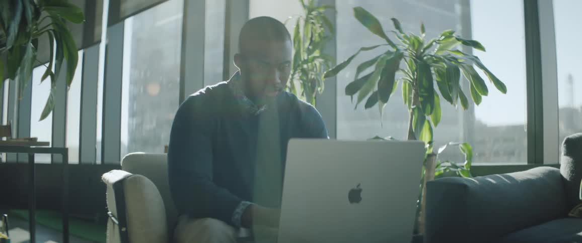 Man sitting on a couch works on a laptop at the office